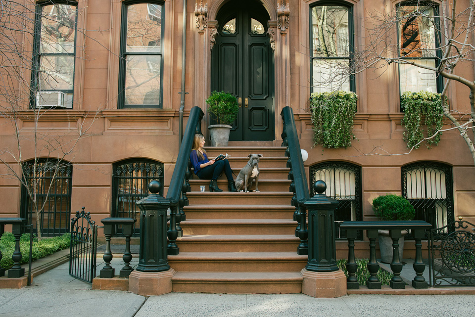 a woman reading a book with her dog on her side